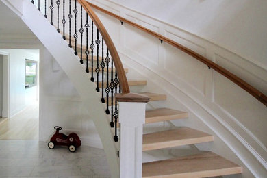 Large transitional wooden curved staircase photo in New York with wooden risers