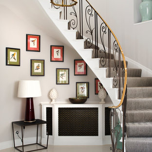 Design ideas for a large classic carpeted curved metal railing staircase in London with carpeted risers.
