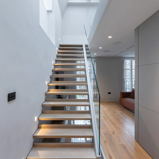 Photo of a contemporary wood straight glass railing staircase in London with open risers.