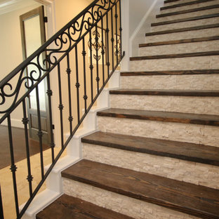 Immagine di una grande scala a rampa dritta mediterranea con pedata in legno, alzata in travertino e parapetto in metallo