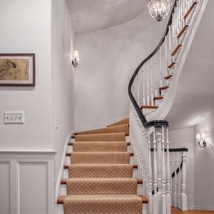 Ispirazione per una grande scala curva chic con pedata in legno e alzata in legno verniciato