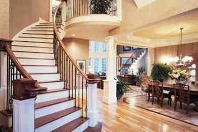 Example of a large wooden curved staircase design in Richmond with metal risers