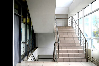 Inspiration for a large modern tiled straight metal railing staircase in London with tiled risers.