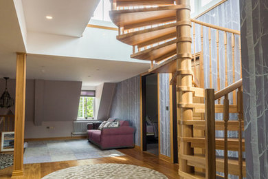 Пример оригинального дизайна: большая винтовая лестница в скандинавском стиле с деревянными ступенями и деревянными перилами без подступенок