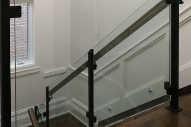 Diseño de escalera recta tradicional con escalones de madera, contrahuellas de madera y barandilla de vidrio
