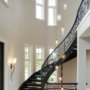 Example of a huge classic wooden curved open and metal railing staircase design in Minneapolis