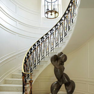 Immagine di un'ampia scala curva tradizionale con pedata in marmo e alzata in marmo
