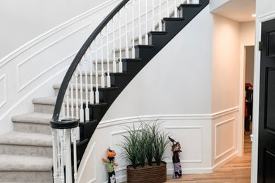 Modelo de escalera curva tradicional renovada de tamaño medio con escalones enmoquetados, contrahuellas enmoquetadas, barandilla de madera y boiserie