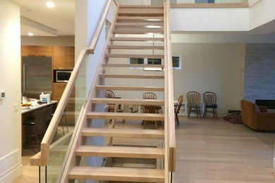 На фото: большая прямая лестница в современном стиле с деревянными ступенями и перилами из смешанных материалов без подступенок