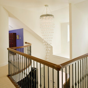 Two Story Foyer Features Crystal Chandelier and Iron Spindle Staircase