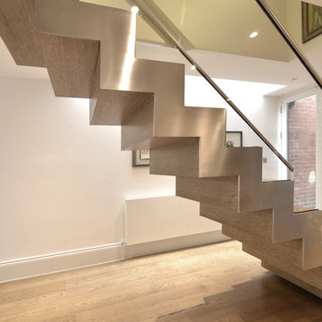 Two straight stairs with offset cantilever timber treads and glass balustrade