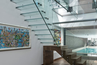 На фото: большая лестница на больцах в современном стиле с стеклянными ступенями и стеклянными подступенками с