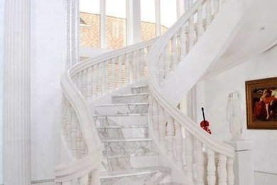 Foto de escalera curva mediterránea grande con escalones de mármol, contrahuellas de mármol y barandilla de madera
