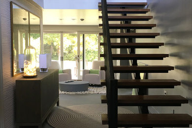 Ejemplo de escalera suspendida contemporánea de tamaño medio con escalones de metal y contrahuellas de madera