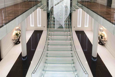 他の地域にあるラグジュアリーな巨大なコンテンポラリースタイルのおしゃれなスケルトン階段 (ガラスの蹴込み板、ガラスフェンス) の写真