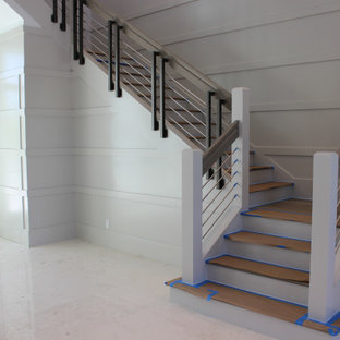 Immagine di una grande scala a "L" classica con pedata in legno, alzata in legno, parapetto in materiali misti e pareti in legno