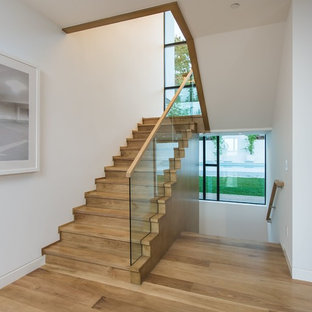 Example of a large trendy wooden u-shaped glass railing staircase design in Los Angeles with wooden risers