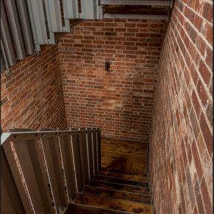 Inspiration pour un escalier sans contremarche design en U de taille moyenne avec des marches en bois, un garde-corps en métal et un mur en parement de brique.