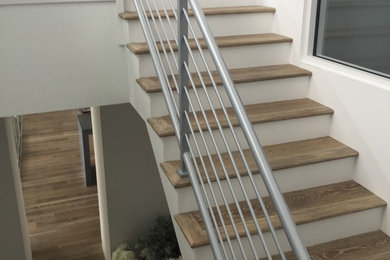 Réalisation d'un escalier peint courbe minimaliste de taille moyenne avec des marches en bois et un garde-corps en métal.