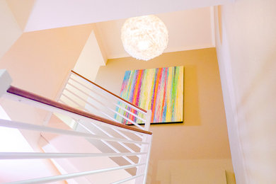 Imagen de escalera en L contemporánea de tamaño medio con escalones enmoquetados, contrahuellas enmoquetadas y barandilla de madera