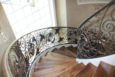 Imagen de escalera curva clásica grande con escalones de madera y contrahuellas de madera