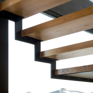 Esempio di una scala sospesa design di medie dimensioni con pedata in legno, nessuna alzata, parapetto in metallo e pareti in legno