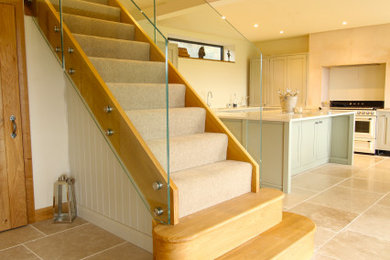Ejemplo de escalera recta actual de tamaño medio con escalones enmoquetados y barandilla de vidrio