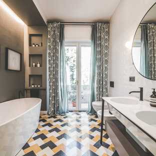 Esempio di una stanza da bagno contemporanea con ante lisce, ante grigie, vasca freestanding, pareti grigie, lavabo integrato, pavimento multicolore, top bianco e due lavabi