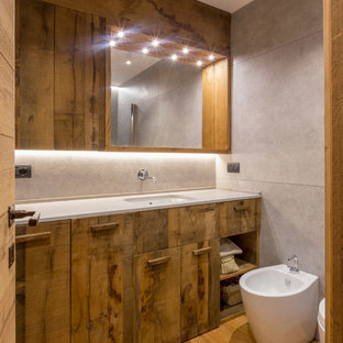 Foto di una stanza da bagno stile rurale con ante lisce, ante in legno scuro, bidè, piastrelle grigie, pavimento in legno massello medio, lavabo sottopiano e pavimento marrone