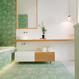 Imagen de cuarto de baño principal, actual, con armarios abiertos, puertas de armario de madera oscura, bañera encastrada, baldosas y/o azulejos verdes, lavabo sobreencimera, encimera de madera, suelo verde, paredes blancas y encimeras beige