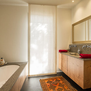 Immagine di una stanza da bagno eclettica con ante lisce, ante in legno scuro, vasca sottopiano, piastrelle grigie, pareti bianche, lavabo sottopiano, pavimento nero e top grigio
