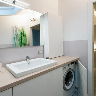Cette image montre une salle de bain minimaliste de taille moyenne avec un placard à porte plane, des portes de placard blanches, un plan de toilette en bois, un mur gris, un sol en carrelage de porcelaine, une grande vasque et un plan de toilette beige.