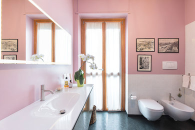 Immagine di una stanza da bagno padronale minimal di medie dimensioni con vasca da incasso, WC sospeso, piastrelle nere, piastrelle a mosaico, pareti rosa, lavabo integrato, top in vetro, pavimento verde e top bianco