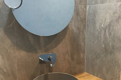 Foto di una piccola stanza da bagno con doccia industriale con ante in legno chiaro, piastrelle grigie, piastrelle in gres porcellanato, pareti grigie, lavabo a bacinella e top in legno