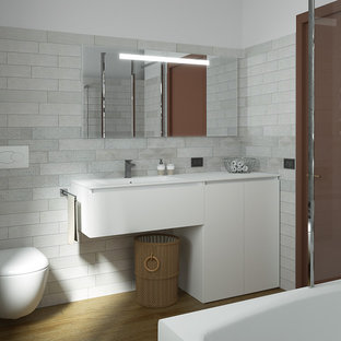 Inspiration for a small modern 3/4 bathroom in Other with flat-panel cabinets, white cabinets, a shower/bathtub combo, a wall-mount toilet, gray tile, porcelain tile, white walls, bamboo floors, an integrated sink, brown floor, an open shower, white benchtops and solid surface benchtops.