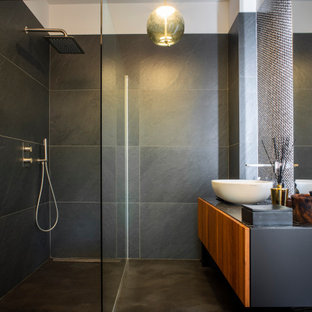 Foto di una stanza da bagno contemporanea con ante lisce, ante in legno scuro, doccia a filo pavimento, piastrelle grigie, lavabo a bacinella, pavimento grigio, doccia aperta, top nero, un lavabo e mobile bagno sospeso