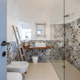Immagine di una stanza da bagno con doccia mediterranea con doccia ad angolo, bidè, piastrelle multicolore, piastrelle di cemento, pareti bianche, lavabo a bacinella, top in legno, pavimento beige, doccia aperta e top marrone