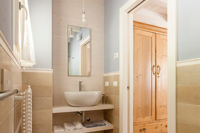 This is an example of a medium sized traditional bathroom in Venice with open cabinets, light wood cabinets, beige tiles, stone slabs, a vessel sink and wooden worktops.