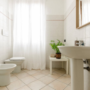 Immagine di una stanza da bagno mediterranea di medie dimensioni con piastrelle bianche, pareti bianche, lavabo a colonna e pavimento beige