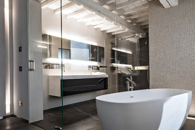 Inspiration för ett stort funkis en-suite badrum, med släta luckor, svarta skåp, ett fristående badkar, grå väggar, grå kakel och mörkt trägolv