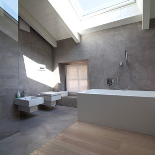 Inspiration för mellanstora moderna vitt en-suite badrum, med släta luckor, vita skåp, ett badkar i en alkov, en kantlös dusch, en vägghängd toalettstol, grå väggar, ett väggmonterat handfat, bänkskiva i akrylsten och med dusch som är öppen