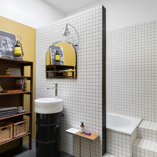 Ispirazione per una stanza da bagno industriale di medie dimensioni con ante nere, vasca da incasso, piastrelle bianche, piastrelle in ceramica, pareti bianche, pavimento in cemento, lavabo a colonna e pavimento grigio