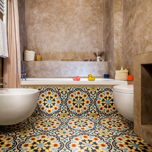 Ispirazione per una stanza da bagno per bambini mediterranea di medie dimensioni con vasca ad alcova, vasca/doccia, bidè, pareti beige, pavimento con piastrelle in ceramica, pavimento multicolore e doccia con tenda