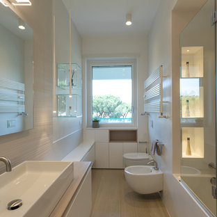 Foto di una stanza da bagno contemporanea con ante lisce, ante bianche, vasca ad angolo, vasca/doccia, bidè, pareti bianche, lavabo da incasso, top in legno, pavimento beige, porta doccia a battente e top beige