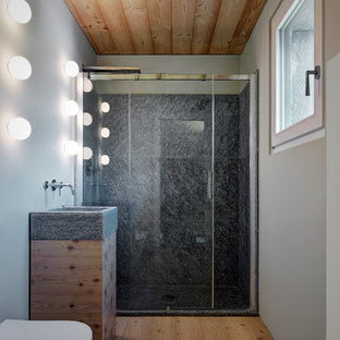 Immagine di una piccola stanza da bagno con doccia contemporanea con ante lisce, doccia alcova, pareti grigie, porta doccia scorrevole, ante in legno chiaro, WC sospeso, piastrelle grigie e parquet chiaro