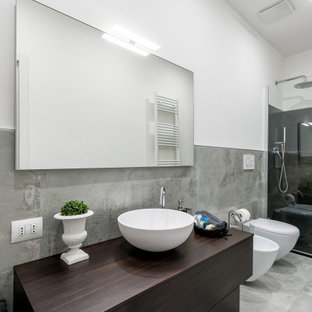 Immagine di una stanza da bagno con doccia design di medie dimensioni con ante lisce, ante in legno bruno, doccia alcova, WC sospeso, piastrelle nere, piastrelle grigie, pareti bianche, lavabo a bacinella, top in legno, pavimento grigio e top marrone