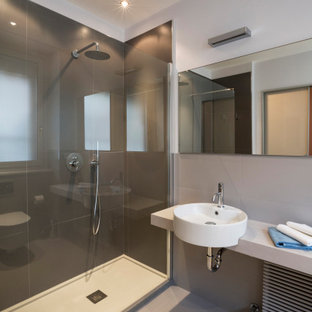 Immagine di una grande stanza da bagno padronale minimal con piastrelle grigie, piastrelle in gres porcellanato, pareti grigie, pavimento in gres porcellanato, lavabo a bacinella, pavimento grigio, top grigio, un lavabo, doccia doppia, WC sospeso e top in cemento