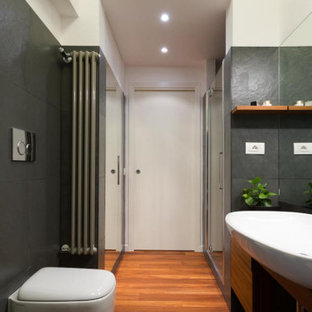 Ispirazione per una stanza da bagno con doccia design di medie dimensioni con ante lisce, ante in legno scuro, doccia alcova, WC sospeso, piastrelle grigie, pareti bianche, lavabo a bacinella, pavimento marrone, porta doccia a battente, top nero, un lavabo e mobile bagno incassato