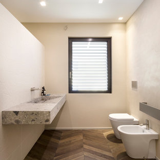 Idee per una stanza da bagno minimal con orinatoio, pareti beige, pavimento in legno massello medio, lavabo integrato, pavimento marrone e top grigio
