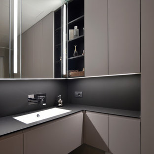 Immagine di una stanza da bagno minimal con ante lisce, ante grigie, lavabo sottopiano e top nero